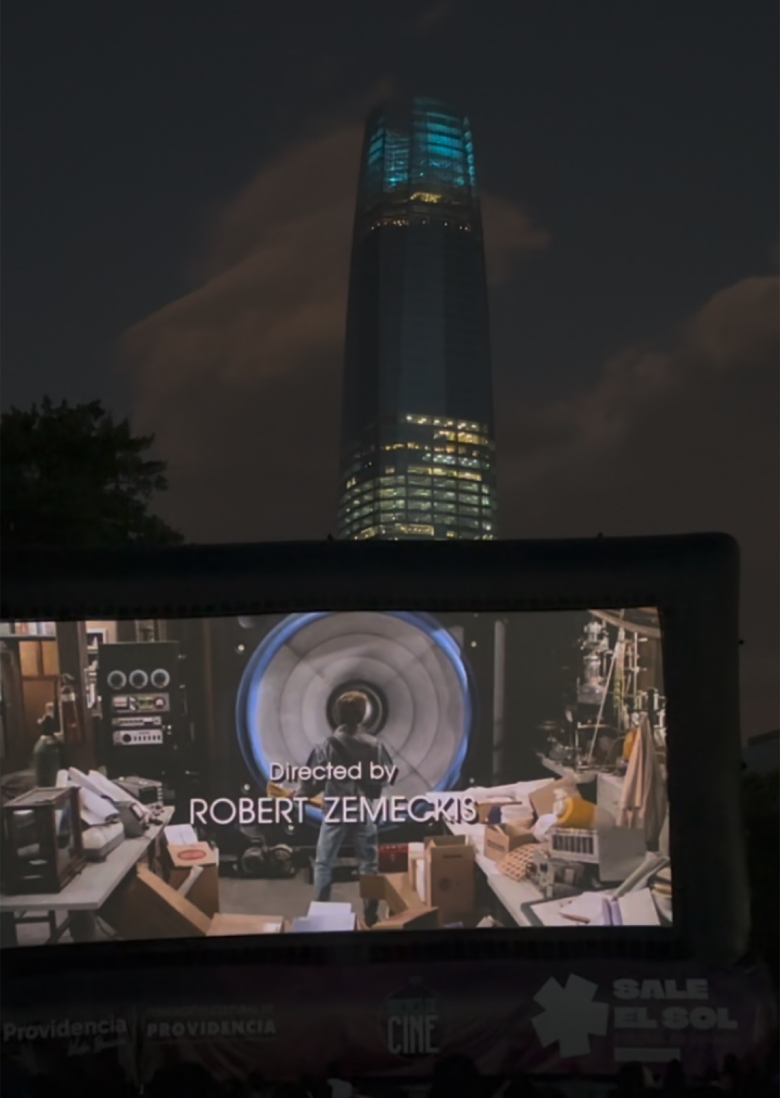 Noches de Cine Providencia — proyección nocturna al aire libre con la Gran Torre Santiago de fondo